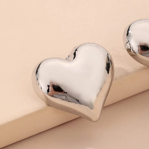 Vue macro des boucles d'oreilles cœur en argent poli avec finition métallique brillante