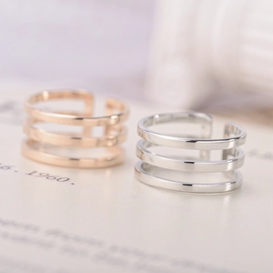 Macro detail of triple-layered silver and rose gold adjustable hollow-line steel rings