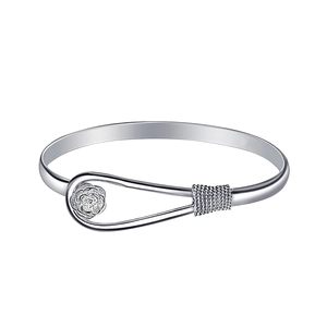 Macro view of silver bracelet with rose flower relief and braided metal texture details