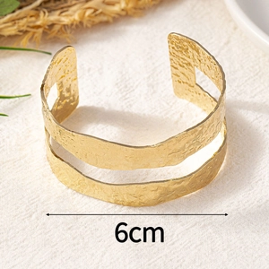 Macro detail of a 6cm wide double-layered gold titanium bracelet with hammered texture