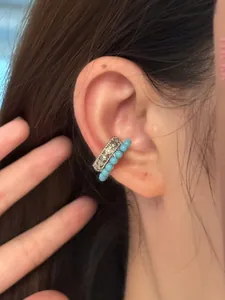 Détail d'un ear cuff à double couche avec des perles bleues et motifs ajourés argentés