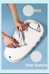 Detail of white plastic washboard featuring dual texture surfaces and soap drainage tray