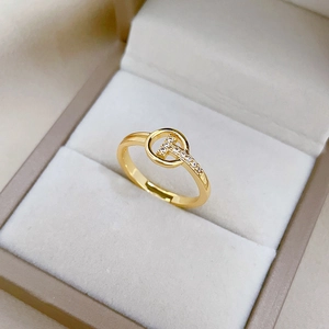 Macro view of gold-plated T-shaped ring with pavé crystals in a grey jewelry box