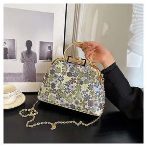 Close-up of floral embroidery shell bag with gold metal frame and chain strap