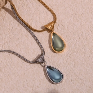 Detailed macro view of waterdrop pendants with teal gemstones on gold and silver snake chains