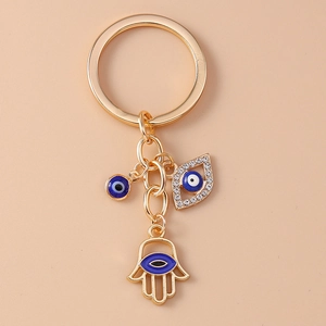 Retro hip-hop gold Hamsa Hand keychain with evil eye charms on beige background