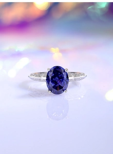 Macro shot of an oval blue gemstone ring with silver wings and shimmering diamond accents