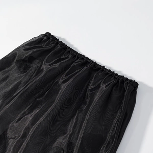 Detalle de la cintura elástica de una falda de malla negra transparente con pliegues finos