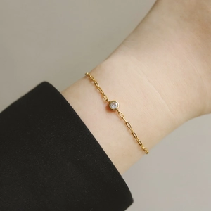 Détail d'un bracelet minimaliste en titane plaqué or 18 carats avec un seul diamant rond