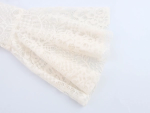 Nahaufnahme der floralen Spitze und des Wellensaums in elegantem Cremeweiß