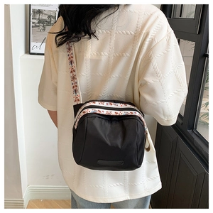 Detail of black nylon shell bag with colorful ethnic embroidered wide shoulder strap