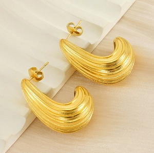 Macro detail of gold-plated stainless steel hoop earrings with pleated shrimp texture