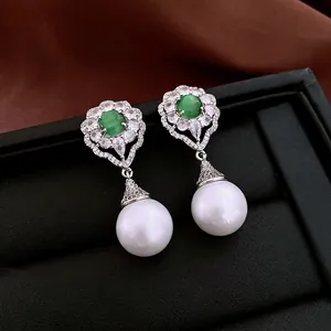 Elegant floral drop earrings with green cat-eye stone and white pearls on black leather