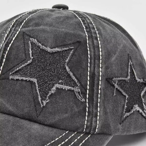 Macro detail of washed grey baseball cap featuring a glittery star patch and vintage stitching