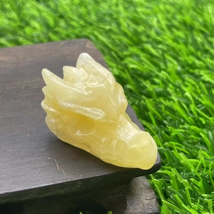 Detailed view of a 4cm translucent yellow natural stone dragon head on a wooden stand