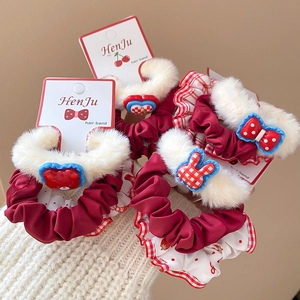 Close-up of four plush hair ties set with red and white patterns on display card