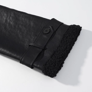 Close-up of black leather coat cuff with thick faux fur trim and buckle detail