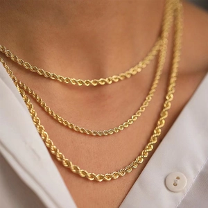 Detailed view of layered gold twist chain necklaces worn over a white shirt