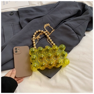Macro detail of yellow bubble-textured acrylic handbag with gold bead chain handle