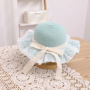 Detail of mint green straw hat featuring delicate white lace trim and bow for girls