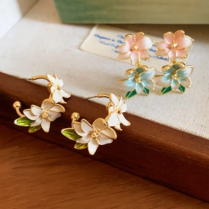 Detail view of floral enamel earrings with intricate gold edges and vintage design