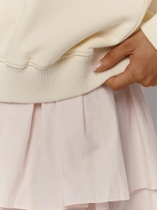 Détail de l'ourlet côtelé du pull en maille crème avec jupe rose à volants
