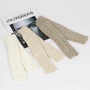 Detail of cable knit arm warmers in white, beige and khaki on a lifestyle magazine