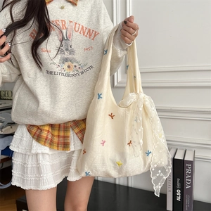 Detail of white canvas tote bag with cherry embroidery and lace ribbon on shoulder strap