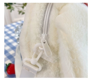 Close-up of the white zipper and strap buckle on the plush avocado crossbody bag