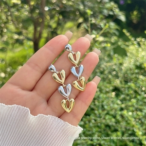 Détail des boucles d'oreilles triple cœur articulé en fini doré et argenté