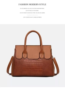 Detail view of caramel brown handbag featuring crocodile embossed pattern and smooth leather