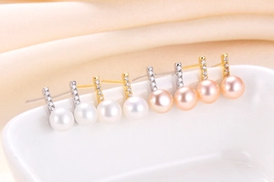 Detailed view of silver bar stud earrings with white and pink pearls and zircons