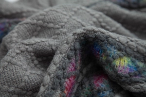 Macro view of grey diamond knit fabric with colorful blended lining on the poncho