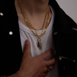 Detail of layered gold titanium necklace with lapis lazuli and feather pendants