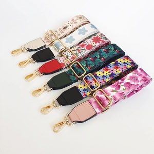 Detail of wide canvas bag straps with diverse floral patterns and gold metal buckles
