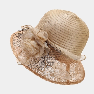 Detail of elegant champagne sun hat with large silk flower, mesh veil and lace brim