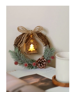 Close-up of a lit wooden cabin and pine cones on a rustic Christmas wreath