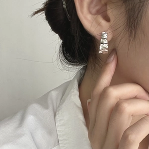 Close-up of minimalist wavy silver hoop earrings featuring unique crinkled foil texture