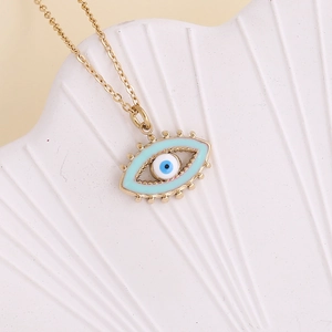 Macro shot of gold Evil Eye pendant with blue enamel on a white textured shell