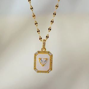 Detail of gold heart pendant necklace with mother of pearl inlay and crystal frame