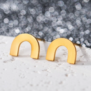 Macro shot of matte gold U-shaped geometric earrings on a white stone base