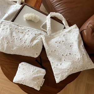 Flat lay of white cotton embroidery tote bag set with floral patterns and matching pouch