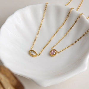 Gros plan de colliers en or 18 carats avec zircon marquise et bords perlés
