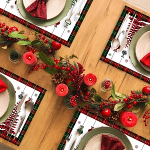 Christmas placemats with red and green plaid borders and snowflake patterns on a wooden table