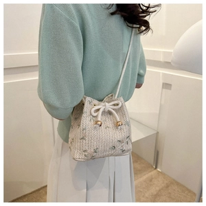 Détail du sac seau tissé avec broderie florale verte et fermeture à cordon