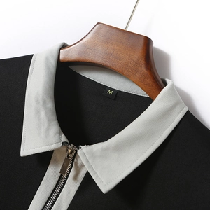 Detailed view of grey collar with metal zipper and knit texture on men's black polo