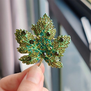 Detailed macro of crystal maple leaf brooch with green and yellow rhinestones