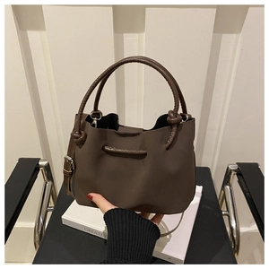 Detail of dark brown tote bag with woven handles and soft matte texture on a chair