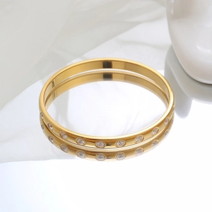 Elegant gold titanium steel bracelet with sparkling round zircons on reflective white surface