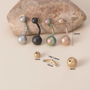 Macro detail of 14G matte stainless steel belly rings with size specs on rock background